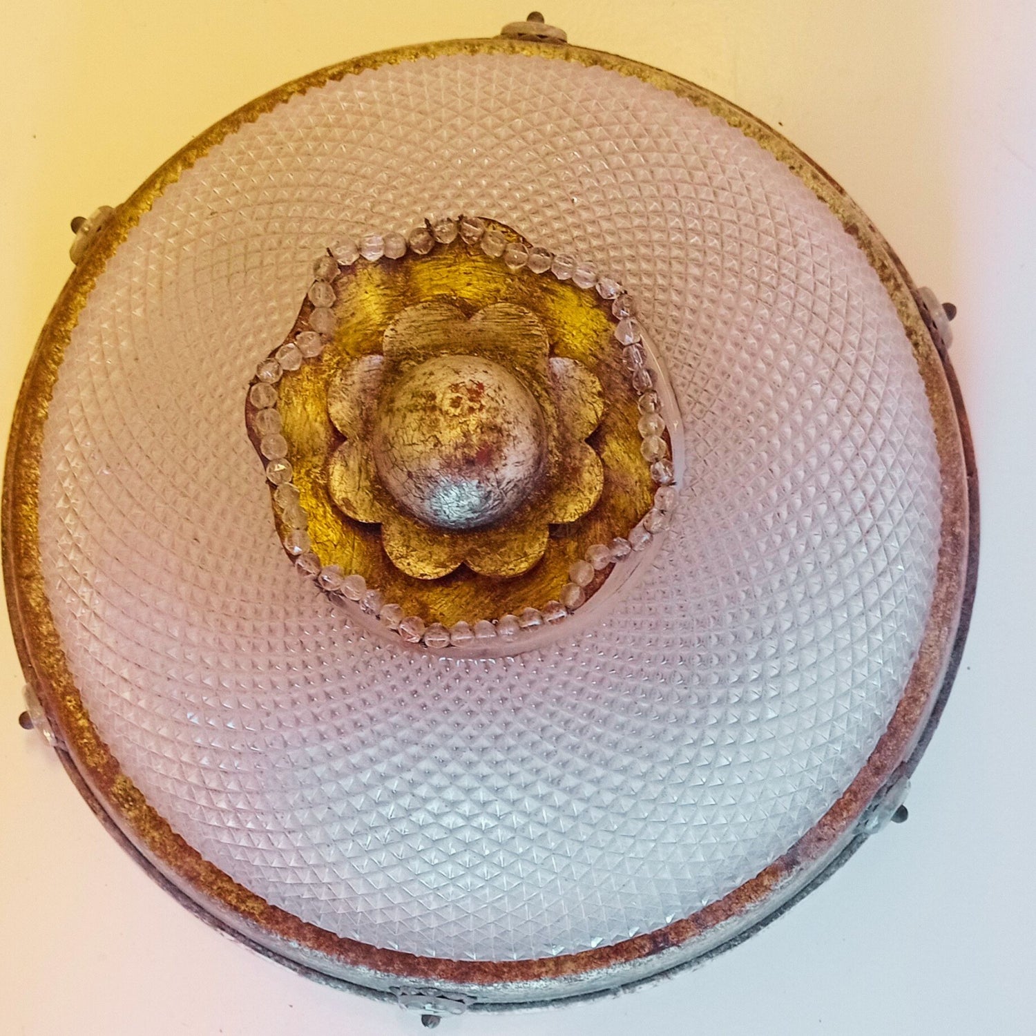Lampada da soffitto vintage con paralume semisferico in vetro pressato a motivo romboidale, bordo in metallo ossidato e decorazione centrale a forma di fiore con perline.